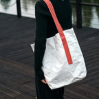Person carrying custom branded Tyvek paper tote bag, sustainable event merch by Wumble Merch Australia